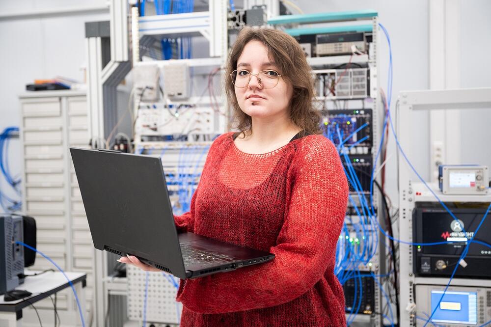 Елизавета Глазкова стоит в квантовой лаборатории с компьютером